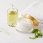 closeup shot of organic oil and cream, dropper, towel and aloe vera slices