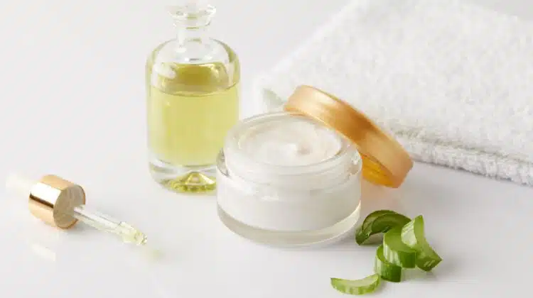closeup shot of organic oil and cream, dropper, towel and aloe vera slices